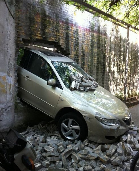 出一个大窟窿,砖头散落一地,但车子整体外观无变形,车头完整无凹陷